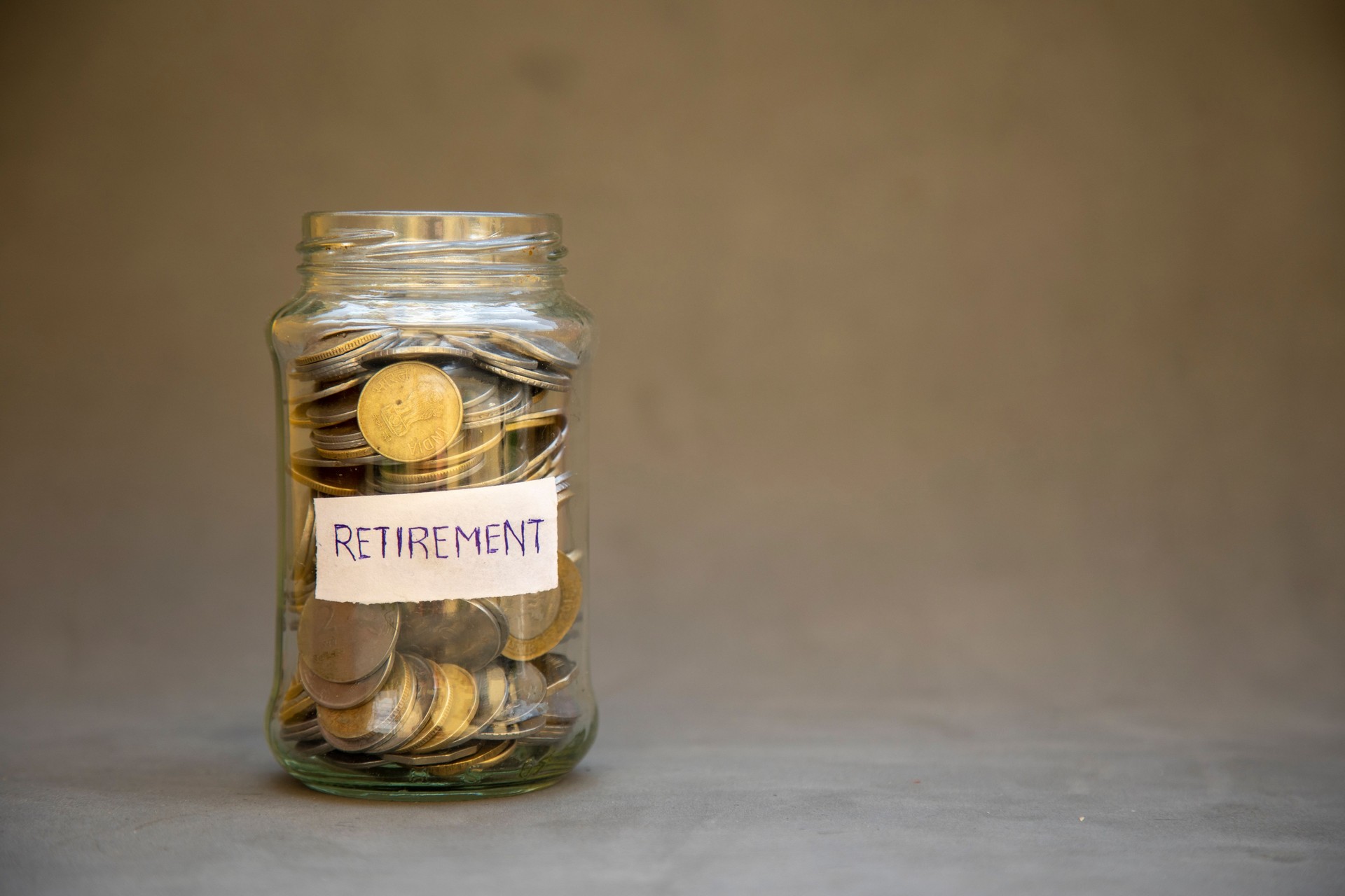 Glass Jar with Coins Labeled Retirement Suggesting Future Savings and Financial Planning.
