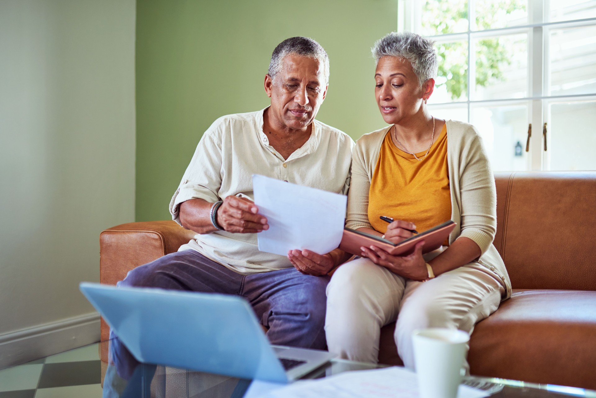 Senior couple planning pension, bills and mortgage payment with inflation paperwork and laptop. Computer, document and elderly man and woman in retirement calculating debt, investment and funds.